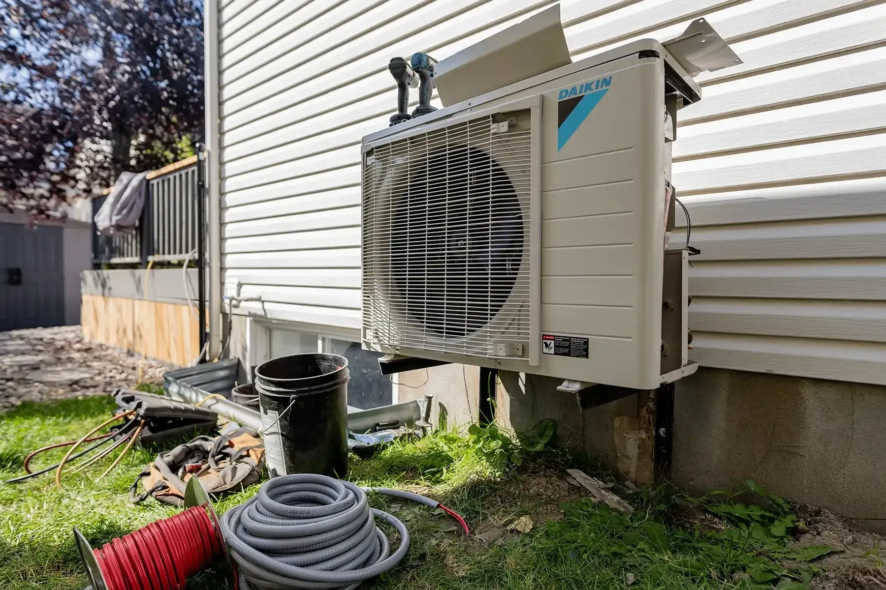 Newly installed outdoor heat pump unit mounted to the siding of a rural Blue Ridge, TX home