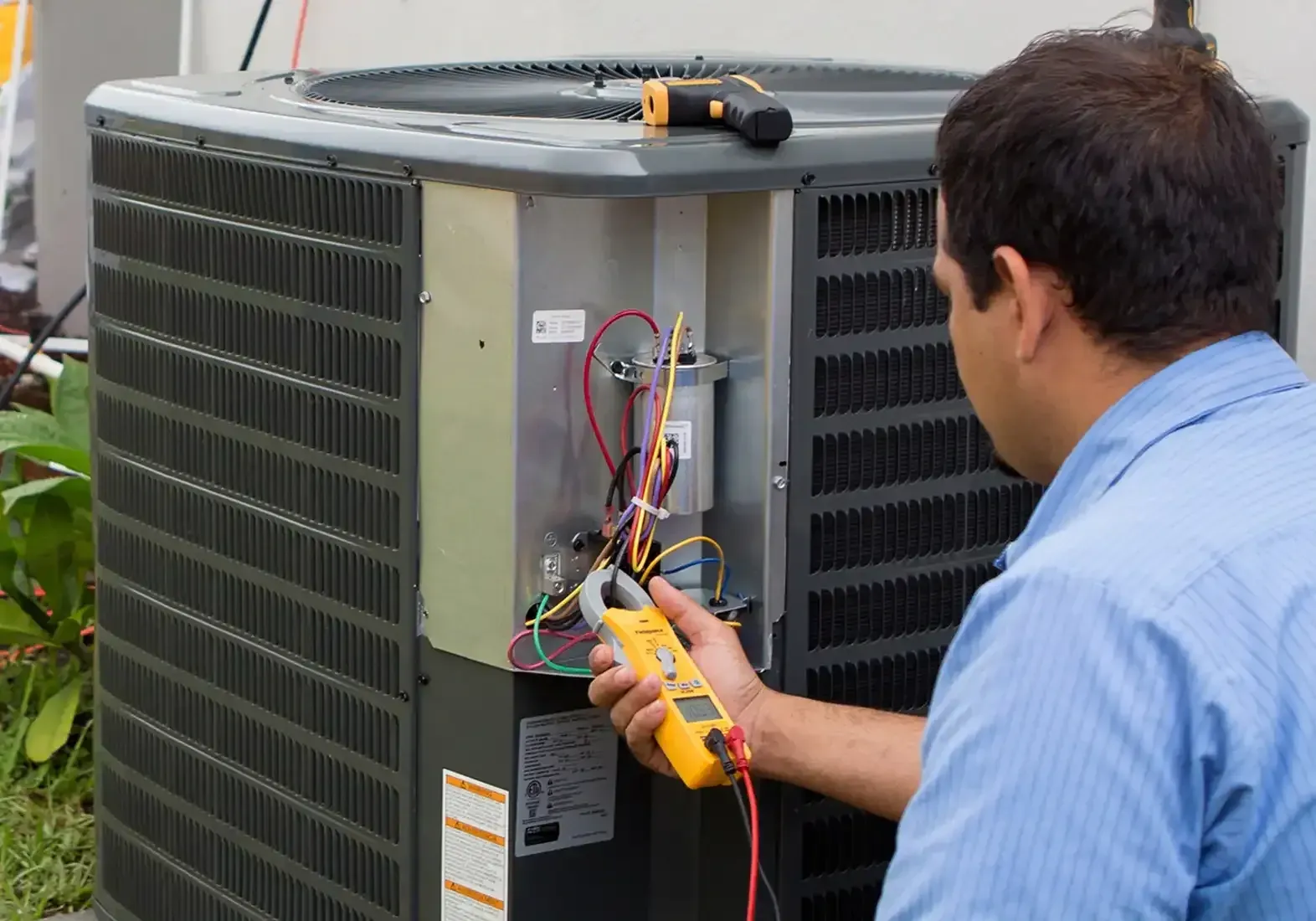 Technician testing capacitor wiring with a meter during an ac repair on a Princeton, TX home