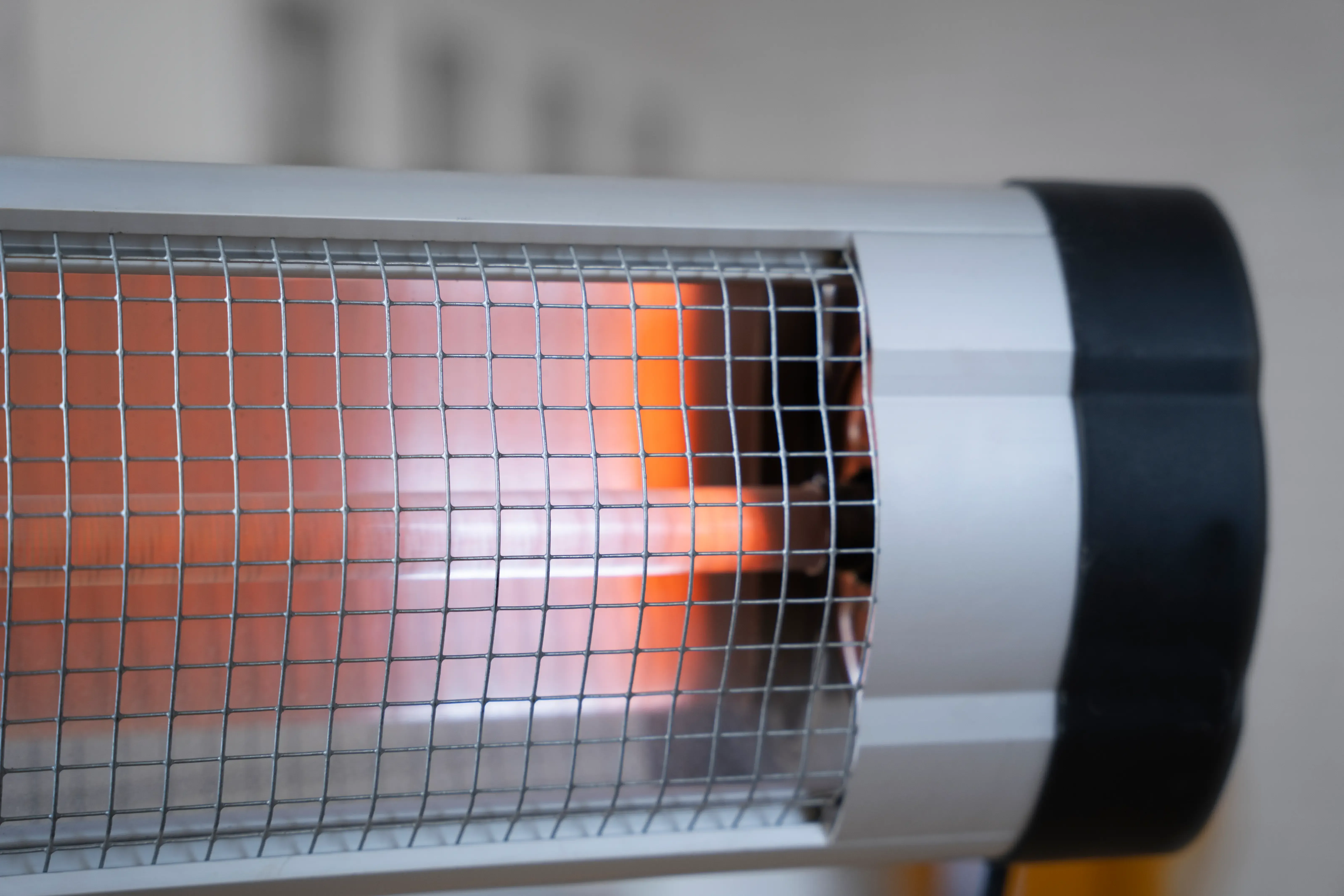 Silver infrared heater with glowing orange element behind a metal grate.